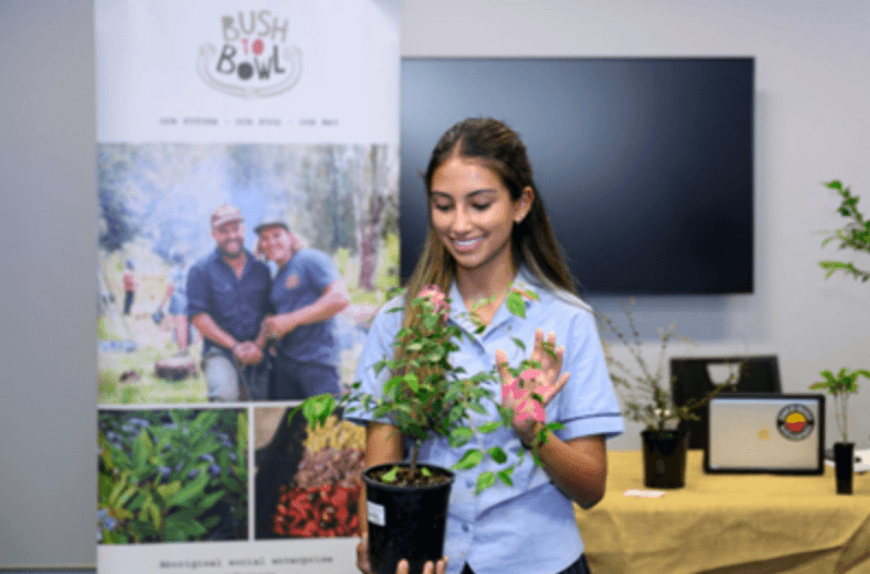 A woman holding a potted plant in front of a table