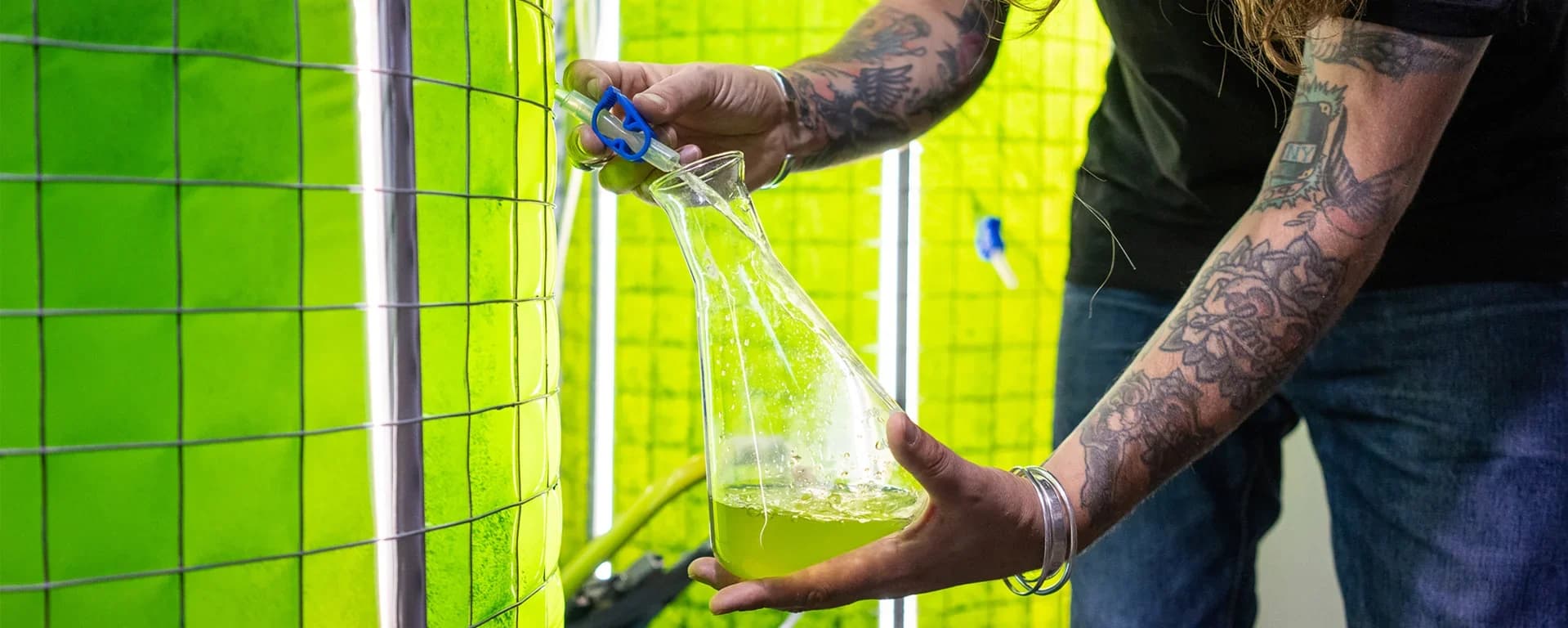 A man with a tattoo on his arm spray painting a wall