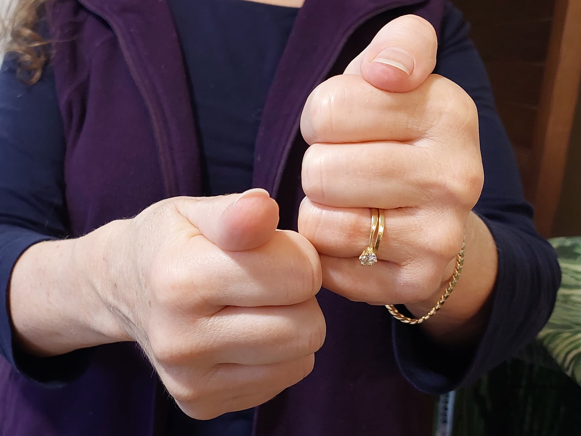 A woman wearing a purple jacket holding a gold ring